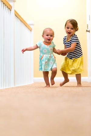 Happy toddler girls running and playing indoorsの写真素材