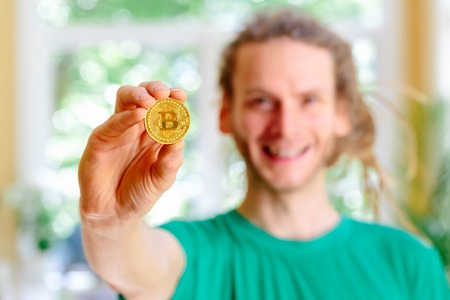 Man holding a physical bitcoin cryptocurrency in his hand outsideの写真素材