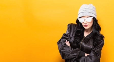 Fashionable woman with attitude in bomber jacket and sunglasses on a yellow backgroundの写真素材