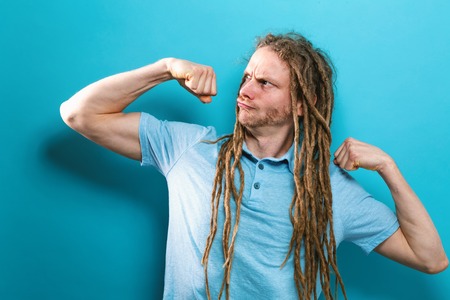 Powerful young man in a success flex pose on a solid backgroundの写真素材