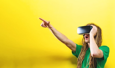 Young man using virtual reality headset on a solid background