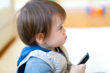 Toddler boy watching television with a remote controlの写真素材