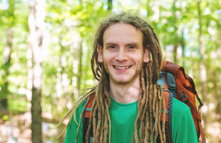 Happy male hiker with backpack trekking through the forestの写真素材