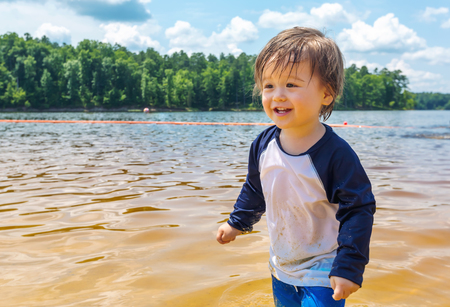 Toddler boy playing in a big lake on a summer dayの写真素材