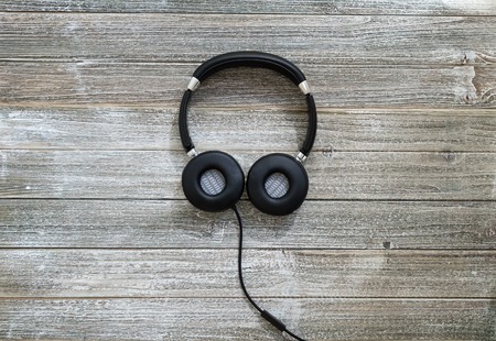 Headphones on a wooden desk overhead viewの写真素材