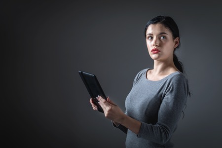 Young woman using her tablet on a gray backgroundの写真素材