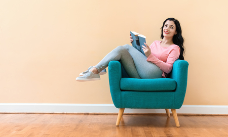 Young woman with a book in a chairの写真素材