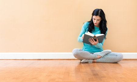 Young woman with a book against a big interior wallの写真素材