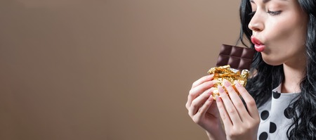 Young woman holding chocolate on a solid backgroundの写真素材