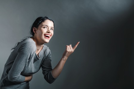 Young woman pointing at something on a solid backgroundの写真素材