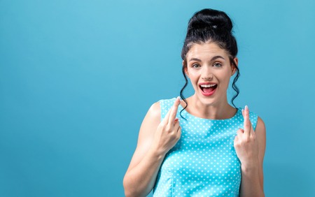 Young woman crossing her fingers and wishing for good luckの写真素材