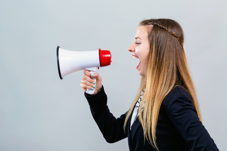 Young woman with a megaphone on a gray backgroundの写真素材