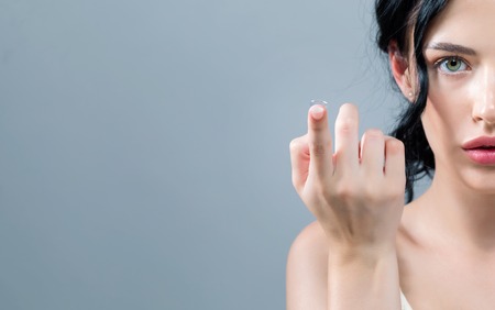 Young woman with contact lenses on a gray backgroundの写真素材