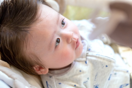 Newborn baby boy sitting in his rocking swing
