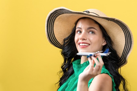 Young woman with toy airplane travel theme on a yellow background