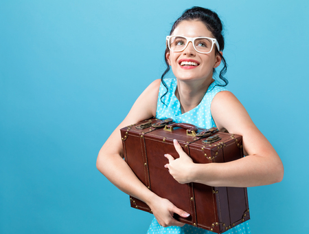 Young woman with a suitcase travel theme on a blue backgroundの写真素材