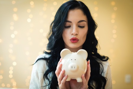 Young woman with a piggy bank on a shiny lights backgroundの写真素材