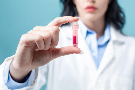 Laboratory scientist researcher with a test vial on a blue backgroundの写真素材