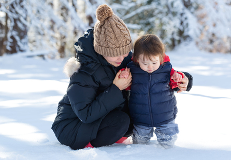 Toddler boy playing in the snow with his motherの写真素材