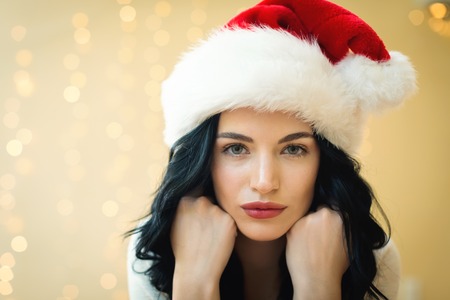Happy woman with a Santa hat on a shiny light backgroundの写真素材