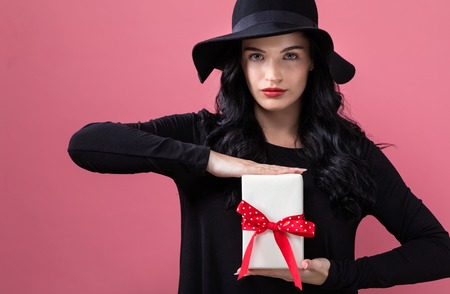 Young woman with a gift box on a pink backgroundの写真素材