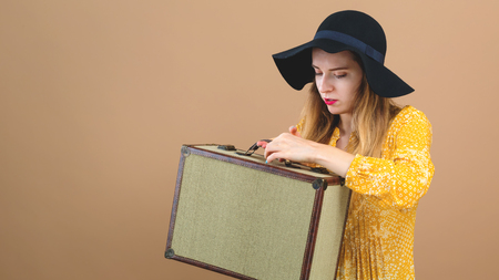 Young woman with a suitcase travel theme on a brown backgroundの写真素材