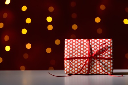 Christmas gift box on a shiny light dark red backgroundの写真素材