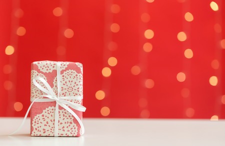 Christmas gift box on a shiny light red background