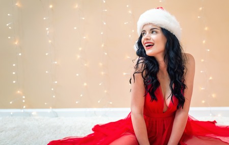 Happy woman with a Santa hat on a shiny light backgroundの写真素材