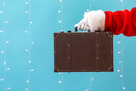 Santa holding a suitcase on a shiny light blue backgroundの写真素材