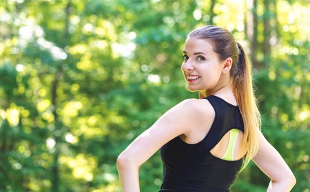 Happy healthy fit woman on a bright summer day in the forest