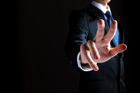 Man in a suit pointing or pressing something on black backgroundの写真素材