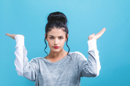 Young woman reaching and looking upwards on a blue backgroundの写真素材