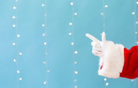 Santa with pointing gesture on a shiny light blue backgroundの写真素材