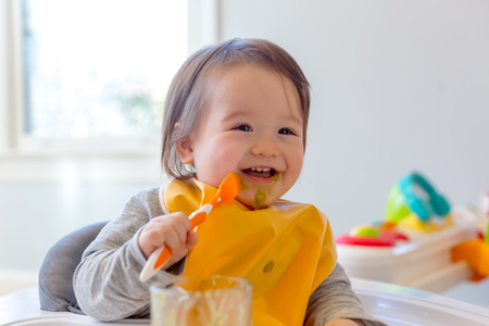 Happy toddler boy smiling while eating a meal