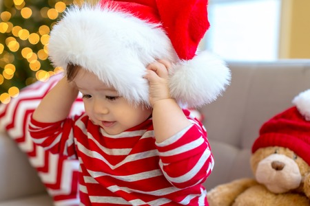 Toddler boy playing with a Santa hat around Christmas timeの写真素材