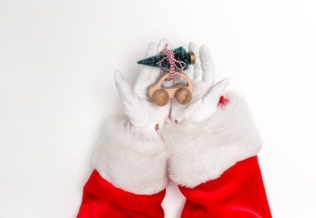 Santa holding a toy car carrying a Christmas tree on a white backgroundの写真素材