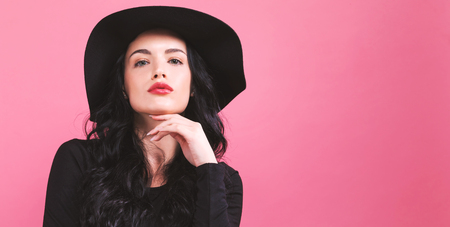Beautiful young woman in a fashionable coat on a pink backgroundの写真素材