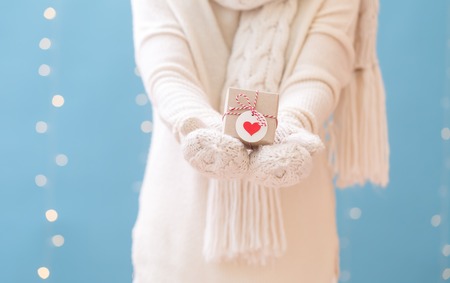Woman holding a Christmas gift box on a shiny light blue backgroundの写真素材