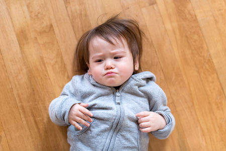 Upset toddler boy laying down in his house