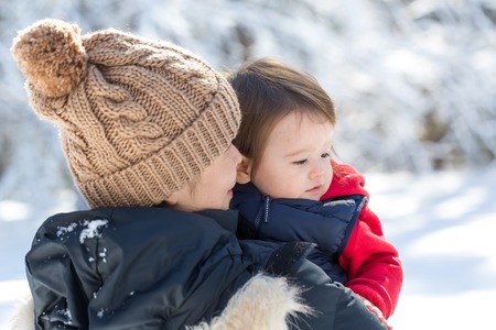 Toddler boy playing in the snow with his mother