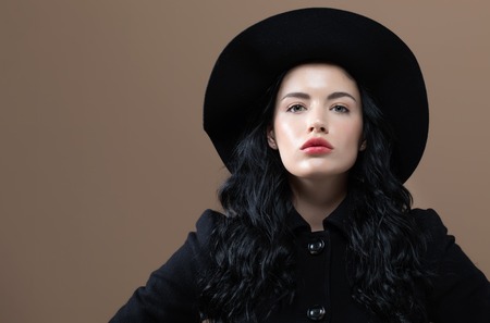 Beautiful young woman in a fashionable coat on a brown background