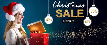 Christmas sale message with young woman with Santa hat opening a gift boxの写真素材