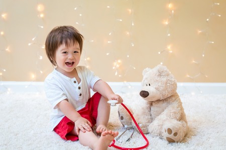 Toddler boy with teddy bear doctor pediatric themeの写真素材