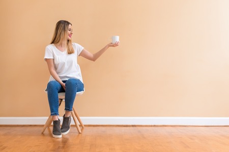 Young woman drinking a cup of coffee in a chairの写真素材