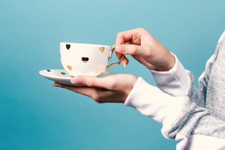 Young woman holding a cup of coffee on a solid backgroundの写真素材