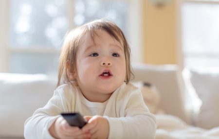 Little toddler boy with a TV remote controlの写真素材