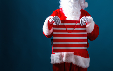 Santa holding a shopping bag on a dark blue backgroundの写真素材