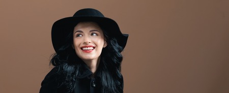 Beautiful young woman in a fashionable coat on a brown backgroundの写真素材