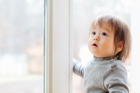 Toddler boy standing in the doorway to his backyardの写真素材